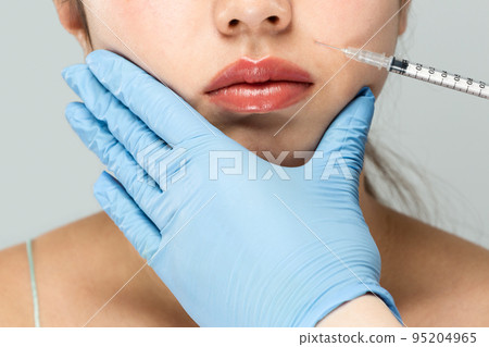 A syringe is applied to the woman's Hōrei line. 95204965