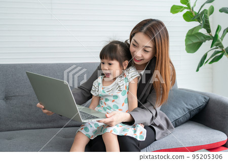Asian mother with her two grandchildren having fun and playing education games online with a digital computer laptop at home in the living room. Concept of online education and caring from parents. 95205306