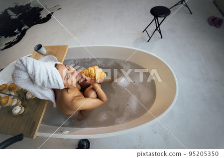 Luxury fashion woman in the morning take breakfast lying in bath Luxury fashion woman in the morning take breakfast lying in bath 95205350