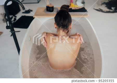 Young woman embracing herself taking a bath view from the back Young woman embracing herself taking a bath view from the back 95205355