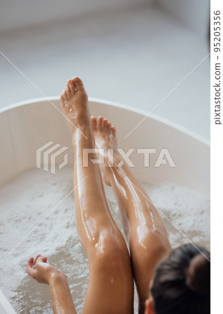 Pretty young woman taking bath at home back view Pretty young woman taking bath at home back view 95205356