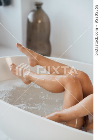 Cropped view of young woman lying in foamy bath Cropped view of young woman lying in foamy bath 95205358