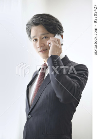 A man in his 50s talking on a smartphone A man in his 50s talking on a smartphone 95205427