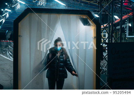 Woman at medic mask is staying in a disinfection tunnel 95205494