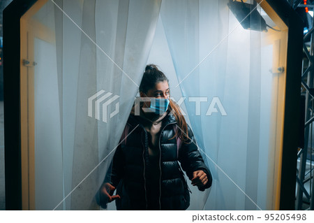 Woman at medic mask is staying in a disinfection tunnel 95205498