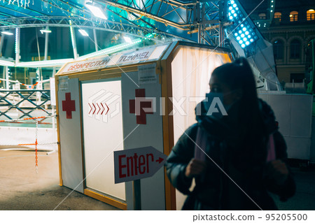Woman in a medic mask is staying at disinfection tunnel Woman in a medic mask is staying at disinfection tunnel 95205500