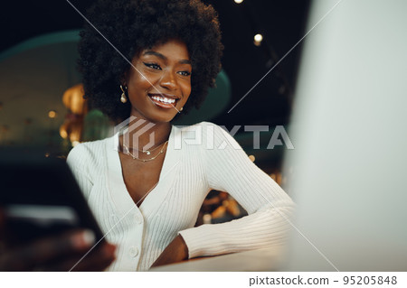 Smiling young african woman sitting with laptop in coffee shop Smiling young african woman sitting with laptop in coffee shop 95205848