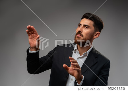 Young Arab businessman working with virtual screen over grey background. Young Arab businessman working with virtual screen over grey background. 95205850
