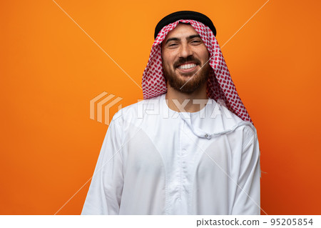 Portrait of young smiling Arab man on orange background Portrait of young smiling Arab man on orange background 95205854