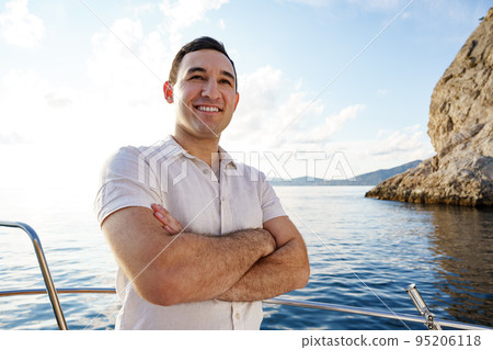 Young man in white shirt standing on the nose yacht in the sea Young man in white shirt standing on the nose yacht in the sea 95206118