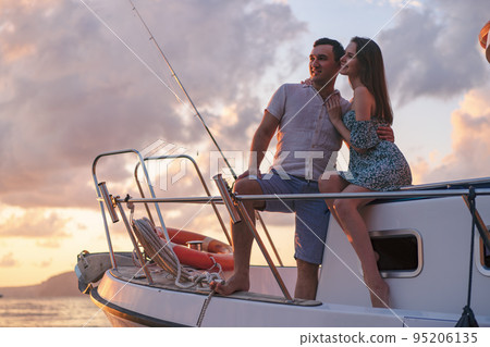 Beautiful couple looking at sunset from the yacht Beautiful couple looking at sunset from the yacht 95206135