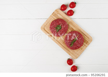 Two raw beef burger patties on wooden board Two raw beef burger patties on wooden board 95206291