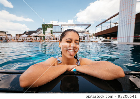 Young woman resting on the edge of swimming pool Young woman resting on the edge of swimming pool 95206541