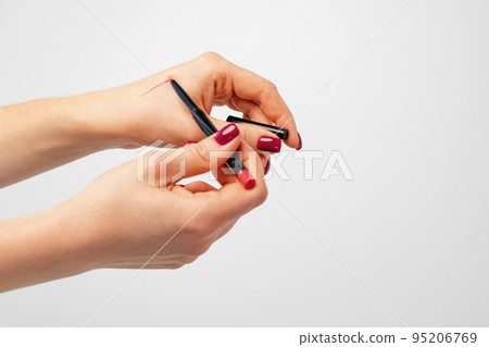 Female palm holding cosmetic pencil against gray background Female palm holding cosmetic pencil against gray background 95206769