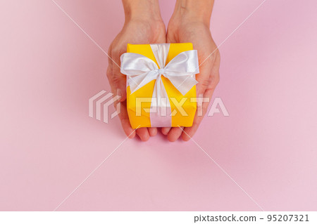 Woman holding gift box on color background 95207321