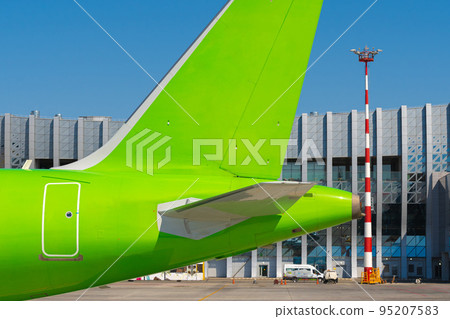 Green passenger airplane at the airport on sunny day 95207583