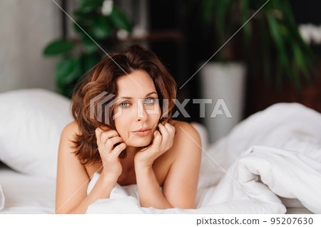 sexy naked brunette woman lying in bed. women's health and attractiveness. sexy naked brunette woman lying in bed. women's health and attractiveness. 95207630