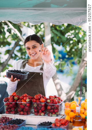 Young positive saleswoman at work, holding currants in her hands 95207927