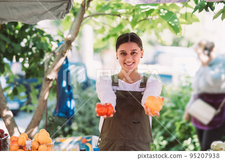 Young saleswoman holding home-grown tomatos in hands Young saleswoman holding home-grown tomatos in hands 95207938