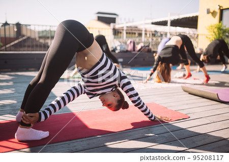 Yogi woman and diverse group of sporty people practicing yoga 95208117