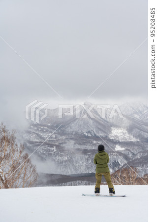 雪飄飄的神奇氛圍的滑雪場和單板滑雪者 95208485
