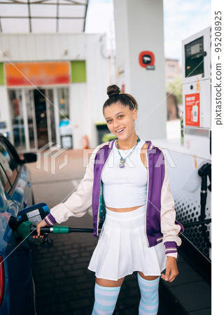 Woman filling her car with fuel at a gas station Woman filling her car with fuel at a gas station 95208925