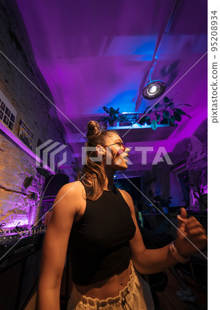 Beautiful female DJ dancing to techno in a small club Beautiful female DJ dancing to techno in a small club 95208934
