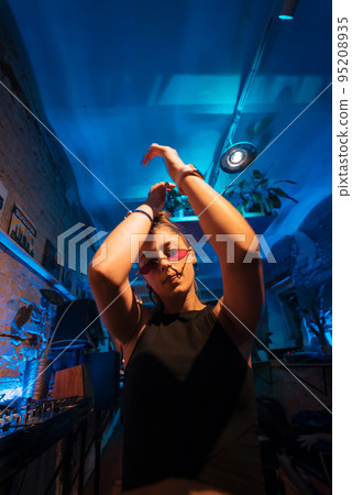 Beautiful female DJ dancing to techno in a small club 95208935