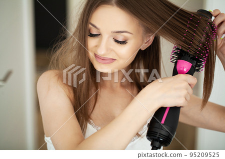 Woman with long hair and healthy skin drying her hair while standing in bathroom. 95209525