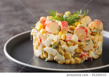 Crab salad with boiled eggs, onion and corn with mayonnaise dressing close-up in a plate. horizontal 95209535