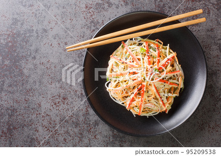 Kani or kanikama salad is a Japanese crab salad that is a delicious mix of crab meat crunchy cucumber and carrots and spicy mayonnaise dressing closeup in the plate. Horizontal top view Kani or kanikama salad is a Japanese crab salad that is a delicious mix of crab meat crunchy cucumber and carrots and spicy mayonnaise dressing closeup in the plate. Horizontal top view 95209538
