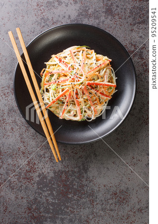 Kani salad is a Japanese version of crab salad made with thin crab sticks and julienned crunchy vegetables, dressed with a spicy mayonnaise closeup in the plate. Vertical top view Kani salad is a Japanese version of crab salad made with thin crab sticks and julienned crunchy vegetables, dressed with a spicy mayonnaise closeup in the plate. Vertical top view 95209541