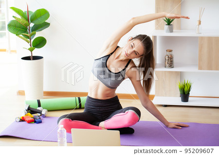 Cheerful active woman doing fitness at home using laptop 95209607
