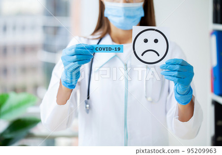 The doctor is holding a card with the Sad Smile symbol in the office of the clinic. 95209963