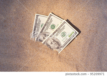 Money dolars half covered with sand lie on beach close-up. Three hundred dollars buried in sand on sea or ocean beach Concept finance money holiday relax vacation. Sunny summer warm wind day. 95209971