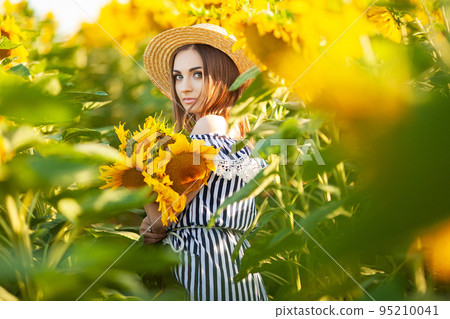 Beautiful young woman in sunflower field on summer day Beautiful young woman in sunflower field on summer day 95210041