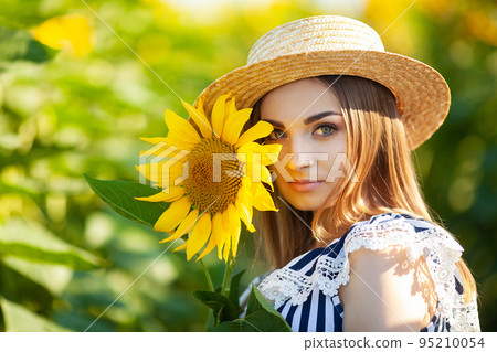 Beautiful young girl enjoying nature on the field of sunflowers at sunset Beautiful young girl enjoying nature on the field of sunflowers at sunset 95210054