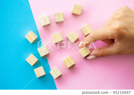 Woman hand arranging empty wood block and copy space on blue and pink background Woman hand arranging empty wood block and copy space on blue and pink background 95210087