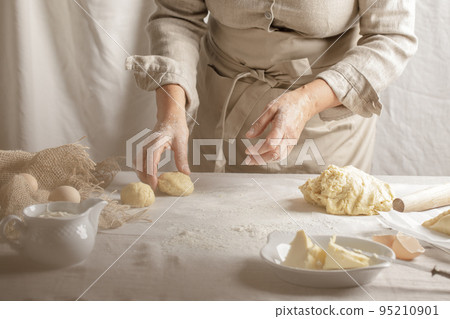 Womens hands, flour and dough. A woman is preparing a dough for home baking. Concept of home cooking with organic and natural ingredients. Zero waste concept 95210901