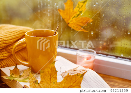 cup of tea, books, autumn leaves and candle on window sill at home cup of tea, books, autumn leaves and candle on window sill at home 95211369