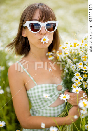 Woman in daisy field with bouquet 95211596