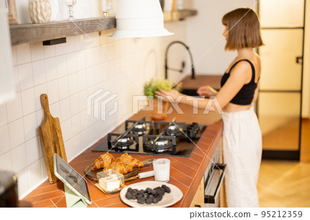 Woman makes a breakfast on kitchen at home Woman makes a breakfast on kitchen at home 95212359
