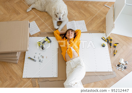 Woman rests with her cute dog, while making repairing at new apartment, 95212447