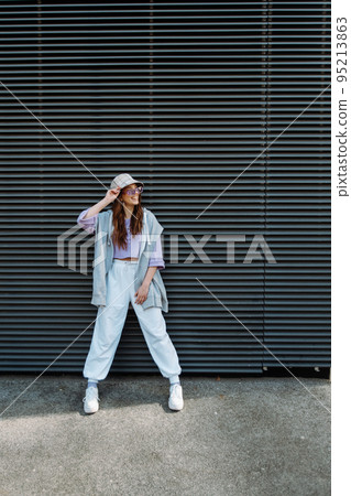 Fashionable funky caucasian girl dancer in sportswear is performing outdoor street dancing motion .  95213863