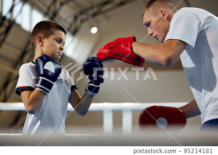 Junior athlete, male boxer training with personal coach at sports gym, indoors. Concept of studying, challenges, sport, hobbies, competition 95214181