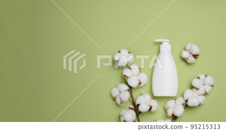 White plastic bottle with pump on a green background. Containers for cosmetics. White plastic bottle with pump on a green background. Containers for cosmetics. 95215313