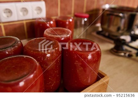 Still life with sterilized jars of freshly canned tomato sauce, passata from organic homegrown juicy tomatoes Rio Grande, or juice upside down on a wooden crate. Canning vegetables for winter. Still life with sterilized jars of freshly canned tomato sauce, passata from organic homegrown juicy tomatoes Rio Grande, or juice upside down on a wooden crate. Canning vegetables for winter. 95215636
