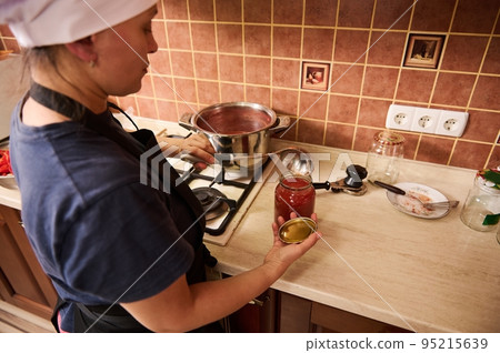 Selective focus. Canning tomatoes for the winter. Canned food. Housewife making preserved from homegrown organic vegetables in the home kitchen 95215639