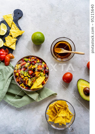 Traditional Mexican vegetable salad - cowboy caviar in bowl with ingredients and nachos on concrete background Traditional Mexican vegetable salad - cowboy caviar in bowl with ingredients and nachos on concrete background 95215640