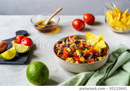 Cowboy caviar is traditional Mexican vegetable salad in bowl with ingredients and nachos on concrete background Cowboy caviar is traditional Mexican vegetable salad in bowl with ingredients and nachos on concrete background 95215641